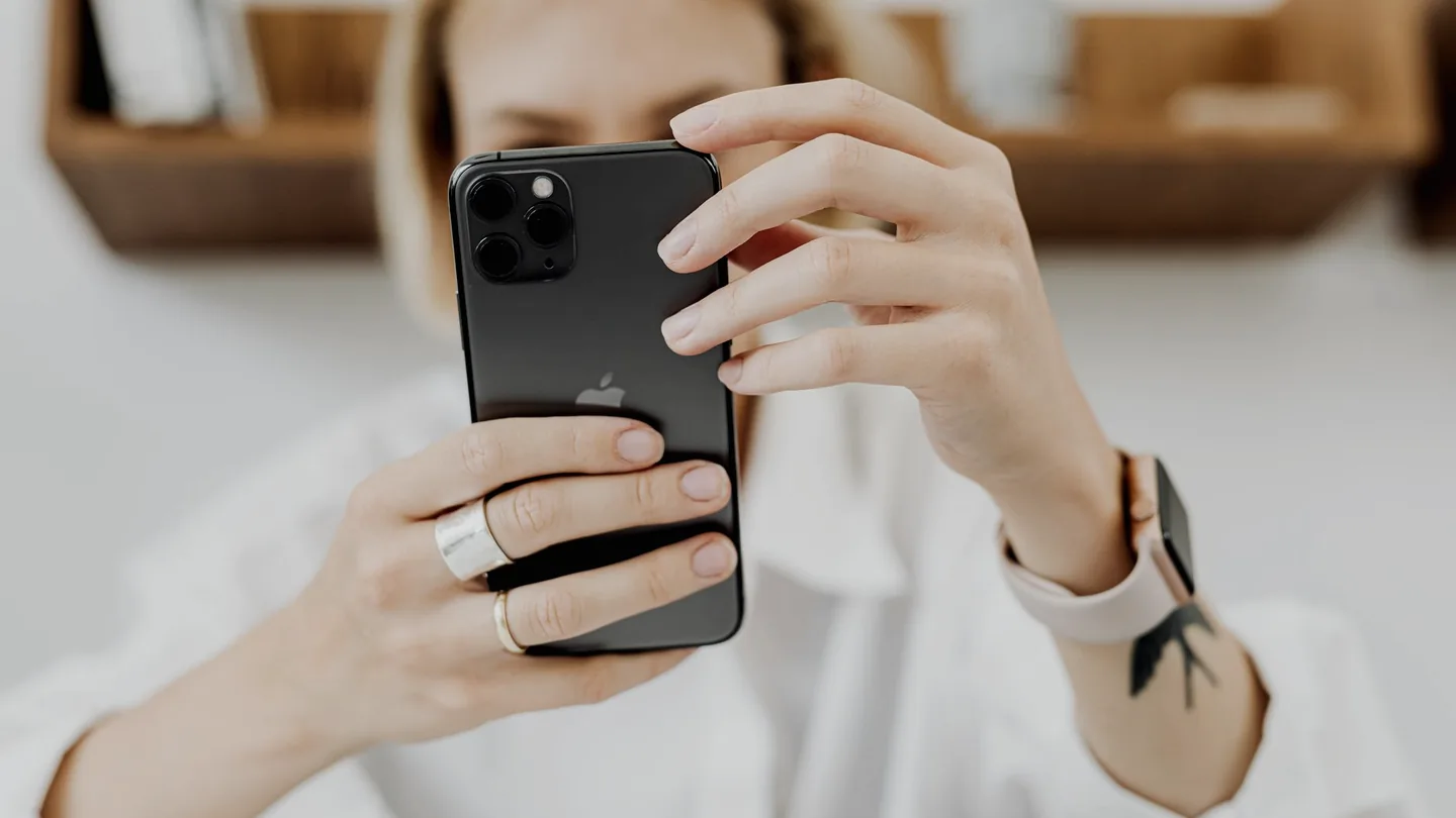 Eine Frau hält ein Smartphone, den Daumen über einem App-Symbol, kurz davor, es zu entfernen