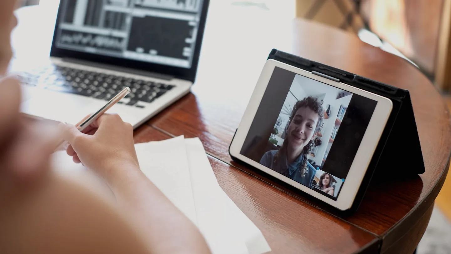 Una persona en un escritorio en casa hablando con un colega en una videollamada desde el portátil